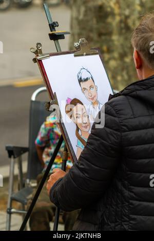 Barcellona, Spagna - 8 aprile 2022: Artista di strada che dipinge una caricatura sulla Rambla di Barcellona (Spagna), approccio selettivo al disegno. Foto Stock