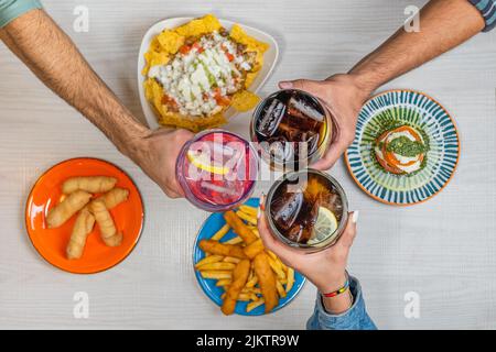 Un'immagine dall'alto della tostatura manuale con varie bevande alcoliche sul tavolo con piatti di cibo Foto Stock