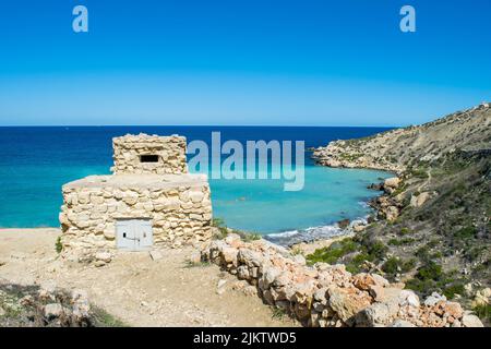 Vecchio posto militare sulla spiaggia che protegge Imgiebah Bay, vicino Selmun, Mellieha, Malta. Le onde blu del mare Mediterraneo sulla spiaggia di sabbia in questo luogo remoto. Foto Stock