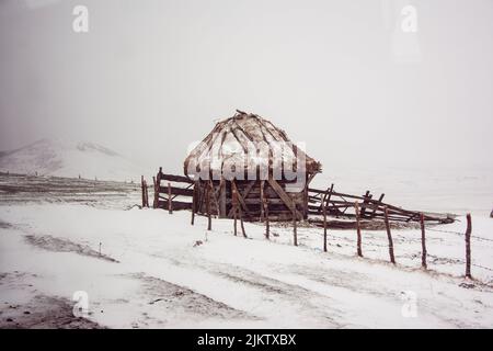 Un paesaggio invernale con una piccola capanna in montagne innevate Foto Stock