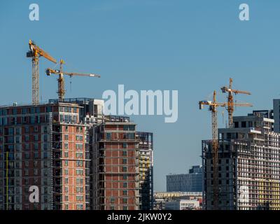 Vista su edifici residenziali alti e moderni e su una costruzione in corso con gru Foto Stock