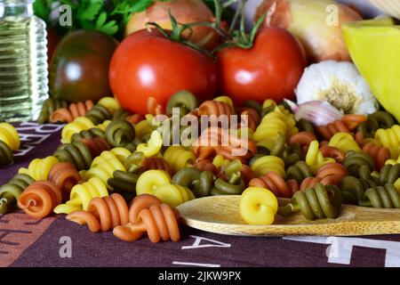 Un cibo sano, pasta colorata, pomodori e altri ingredienti, che forniscono benessere al nostro corpo. Foto Stock