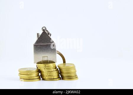 Un primo piano di monete in euro impilate con un portachiavi in metallo sopra di esse su sfondo bianco Foto Stock