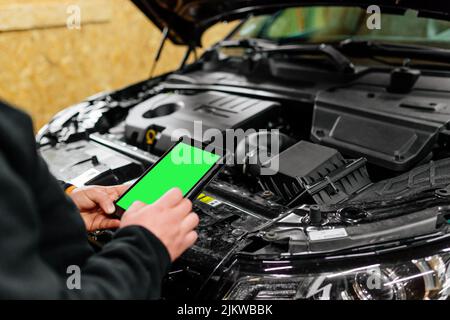 Meccanico dell'auto con tablet che esegue la diagnostica per rilevare il malfunzionamento. Negozio di auto moderne Foto Stock