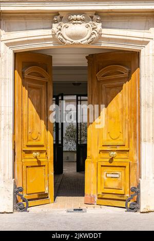 Parigi, una porta di legno aperta, bella facciata decorata, con un incantevole cortile Foto Stock