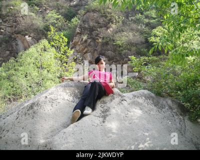 Una ragazza che giace su una roccia della valle di Duijiu, Pechino, CH Foto Stock