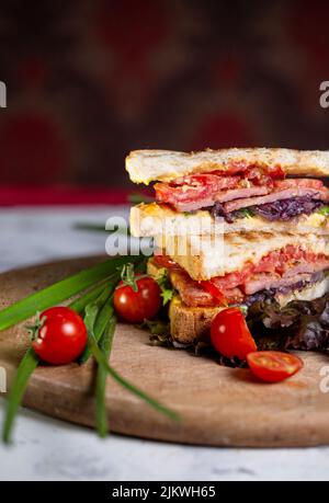 sandwich croccante succoso con prosciutto e verdure a bordo. Foto Stock