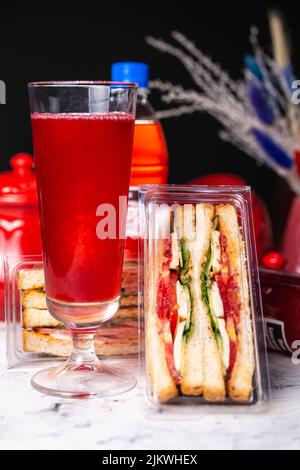 sandwich con farcitura in confezione di plastica. spuntino veloce con una bevanda. Foto Stock