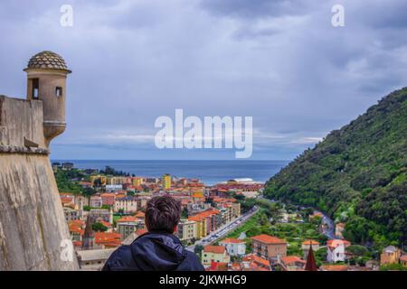 Una vista posteriore di un uomo che indossa una giacca che guarda il paesaggio urbano in Italia Foto Stock