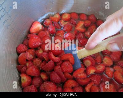 Gusto d'estate: Dopo aver seminato per una notte con zucchero, queste fragole vengono mescolate delicatamente prima di bollire rapidamente per fare la marmellata di fragole. Foto Stock