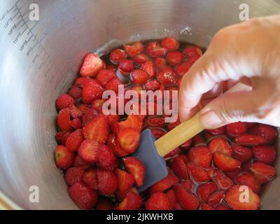 Gusto d'estate: Dopo aver seminato per una notte con zucchero, queste fragole vengono mescolate delicatamente prima di bollire rapidamente per fare la marmellata di fragole. Foto Stock