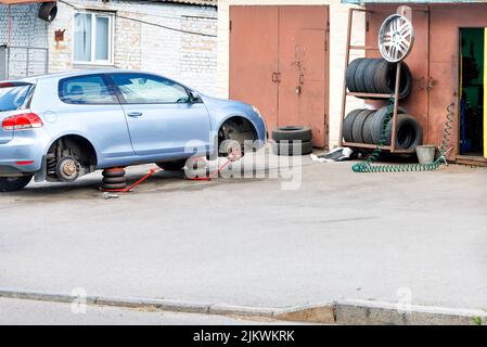 Officina pneumatici e sostituzione delle vecchie ruote su una vettura. Da un lato, l'auto è su jack pneumatici. Spazio di copia. Foto Stock