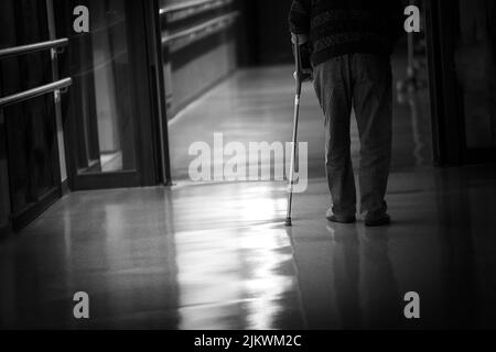 Uomo con un bastone che cammina in un corridoio di una casa di riposo. Foto Stock