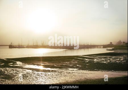 Un molo industriale sul mare con bassa marea durante l'ora d'oro Foto Stock
