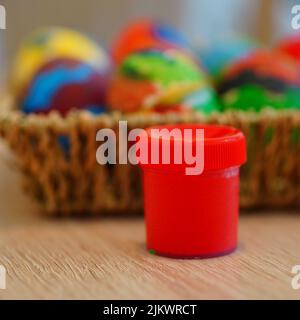 Un focus selettivo sparato di una vernice rossa presso il cesto di paglia con le uova colorate di Pasqua Foto Stock