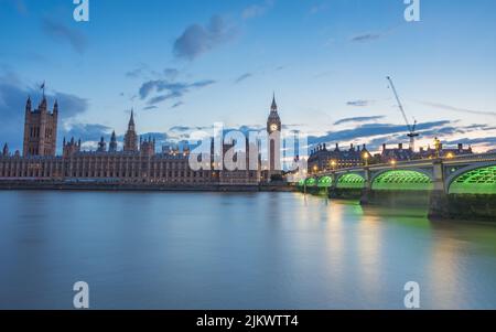 La parte inferiore del Ponte di Westminster si illumina di verde dopo il tramonto a Londra nel luglio 2022 mentre conduce verso il Parlamento e la Grande Be Foto Stock