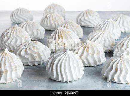 meringa fatta in casa cosparsa di noci su un tavolo grigio, fuoco selettivo, vista laterale. cottura in casa. primo piano di meringa con spazio copia. Foto Stock