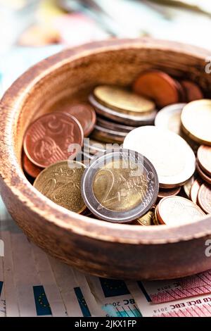 Monete in euro in ciotola su banconote in euro in carta Foto Stock