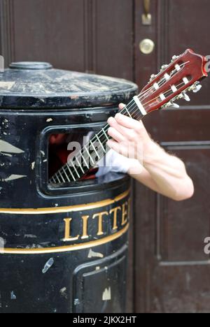 Uomo che suona il busking di chitarra a Cambridge Inghilterra all'interno di un vecchio cestino Foto Stock