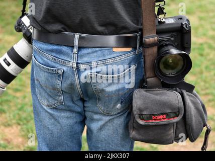 Un fotografo di giornale con fotocamere Canon e una borsa per fotocamera Domke scatta fotografie in un festival all'aperto a Santa Fe, New Mexico. Foto Stock