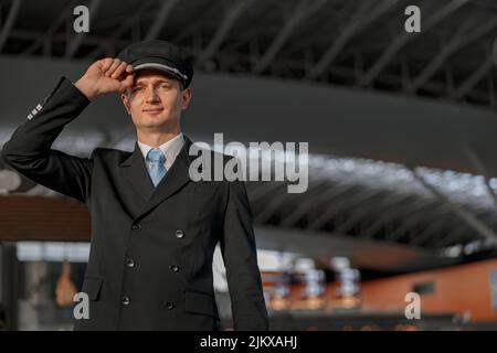 Sorridente pilota maschio in uniforme in piedi nel terminale Foto Stock