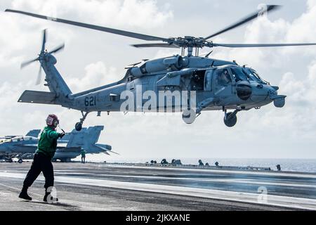 4 luglio 2022 - China Sea - un elicottero MH-60s Sea Hawk attaccato ai Golden Falcons di Helicopter Sea Combat Squadron (HSC) 12 decollo dal ponte di volo dell'unica compagnia aerea statunitense USS Ronald Reagan (CVN 76). HSC 12, originariamente fondata come Squadrone dell'Anti-Submarine Elicottero (HS) 2 il 7 marzo 1952, è il più antico squadrone attivo di elicotteri Navy. Ronald Reagan, il fiore all'occhiello del Carrier Strike Group 5, fornisce una forza pronta per i combattimenti che protegge e difende gli Stati Uniti, e sostiene alleanze, partnership e interessi marittimi collettivi Foto Stock