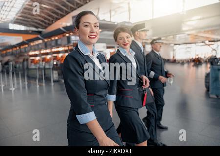 Due assistenti di volo e piloti che camminano attraverso il terminal per l'aereo Foto Stock