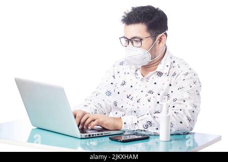 uomo d'affari che usa la maschera da portare con il laptop Foto Stock