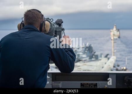 11 luglio 2022 - Philippine Sea - Operations Specialist Seaman Kurt Goldsmith, di Dunedin, Nuova Zelanda, osserva il riapprovvigionamento della flotta militare Sealift Command USNS Yukon (T-AO 202) come unico vettore di aerei della Marina degli Stati Uniti, USS Ronald Reagan (CVN 76), si avvicina per condurre un rifornimento-in mare. Durante l'evoluzione, Yukon trasportò merci e carburante a Ronald Reagan tramite rifornimento verticale e collegato. Ronald Reagan, l'ammiraglia del Carrier Strike Group 5, fornisce una forza pronta per i combattimenti che protegge e difende gli Stati Uniti, e sostiene le alleanze, partnershi Foto Stock