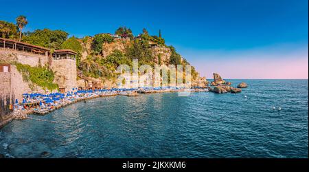 21 giugno 2022, Antalya, Turchia: Popolare spiaggia di Mermerli con ombrelloni e persone che nuotano e riposano vicino al centro storico di Antalya Foto Stock