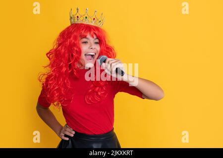 bambino sorridente in corona con microfono su sfondo giallo Foto Stock