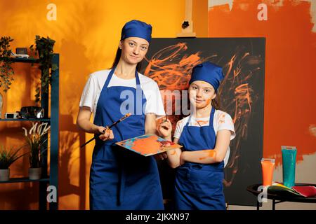 Ritratto di donna e bambino creazione capolavoro su tela con acquerello pittura e acquarelle vassoio di miscelazione. Artisti con capacità creative e visione pittura grafica, utilizzando il colore arancione e pennello. Foto Stock