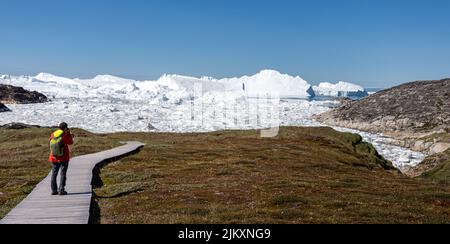 Passerella di legno attraverso la tundra artica che conduce al icefjord di Ilulissat in Ilulissat, Groenlandia, il 17 luglio 2022 Foto Stock