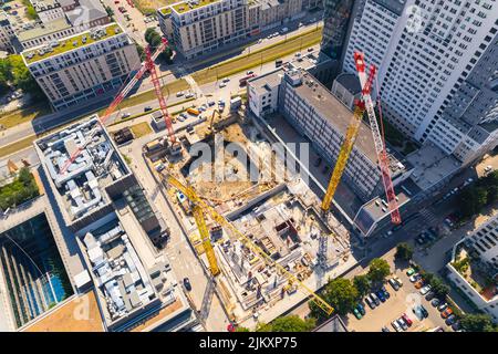 Lavoratori edili che costruisce unità abitative o nuovi grattacieli tra due edifici. Tre gru viste dal punto di vista dei droni aerei. Foto di alta qualità Foto Stock