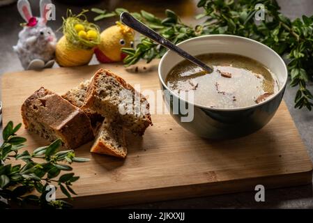 Un primo piano di una tradizionale zuppa di segale acida polacca con pane Foto Stock