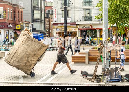 Riciclaggio informale adolescente lavoratore trascinando grande mano-tirato carrello. Raccoglitori di rifiuti riciclabili a Fatih, Istanbul, Turchia Foto Stock