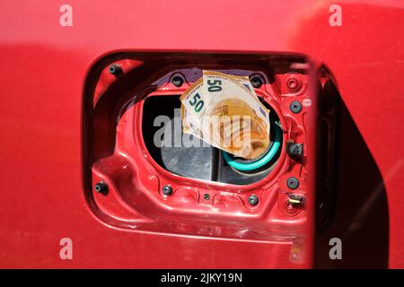 Cinquanta banconote in euro in un serbatoio carburante per auto, concetto di spese di trasporto. Foto Stock