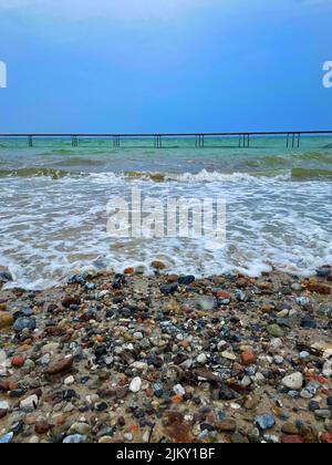 Uno scatto verticale di un lungo molo sulla costa del mare in una giornata buia Foto Stock