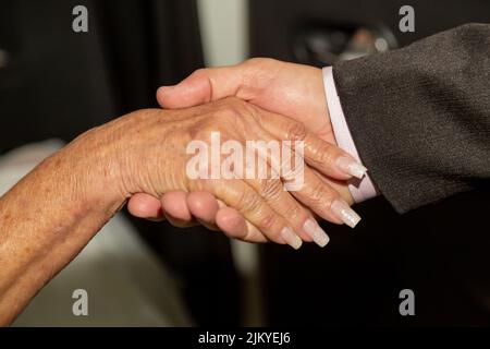 Un primo piano delle mani di un uomo e di una donna anziani che fanno una stretta di mano Foto Stock