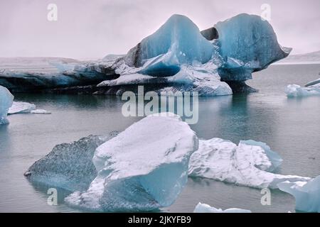 Grandi iceberg blu e nero galleggiano sul Lago del Ghiacciaio Fjallsarlon, Islanda. Foto Stock