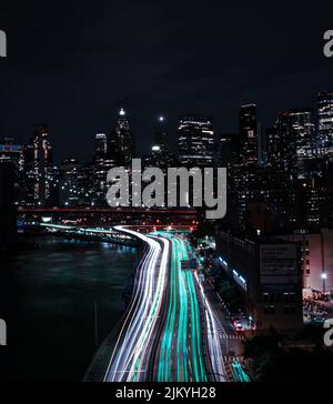 I sentieri leggeri di automobili su una strada circondata da edifici di notte Foto Stock