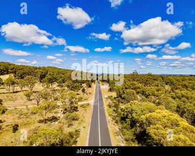 Una pittoresca vista aerea della Glen Innes Road che attraversa le Rummery Hills nel nuovo Galles del Sud, Australia, su un cielo blu nuvoloso Foto Stock