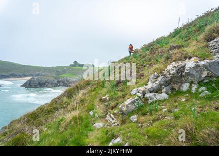 Una giovane donna con il figlio che cammina verso Playa de Troenzo e Playa de la Tayada sulla penisola di Borizu nella città di Llanes. Asturie. Spagna Foto Stock