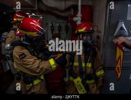 I marinai DELL'OCEANO PACIFICO (30 luglio 2022), assegnati al cacciatorpediniere missilistico guidato di classe Arleigh Burke USS Gridley (DDG 101) combattono un incendio simulato durante un esercizio generale. Abraham Lincoln Carrier Strike Group sta conducendo operazioni di routine nella flotta degli Stati Uniti 3rd. (STATI UNITI Foto Navy di Mass Communication Specialist 2nd Classe Colby A. Mothershead) Foto Stock