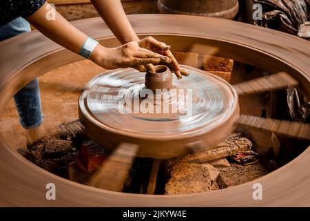 Un colpo lento di velocità dell'otturatore di una mano del vasaio che fa una pentola da una rotella della ceramica. Foto Stock