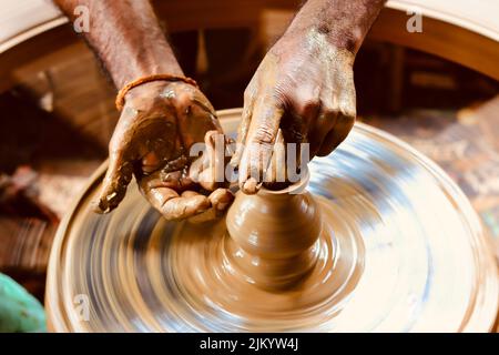 Un colpo lento di velocità dell'otturatore di una mano del vasaio che fa una pentola da una rotella della ceramica. Foto Stock