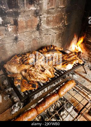 Un boccetto ad angolo alto di pollo e salsicce che vengono cucinati su una griglia Foto Stock