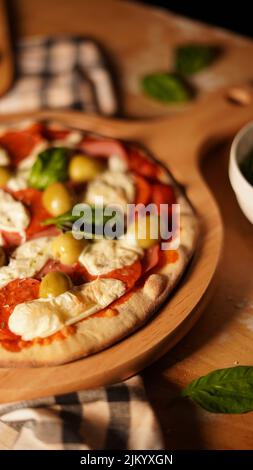 Un colpo verticale di una pizza margarita appena fatta su un asse di legno Foto Stock