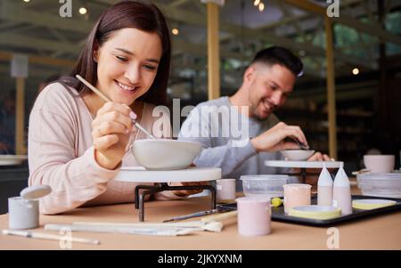 Non ho mai avuto tanto divertimento in un appuntamento: Una giovane coppia che dipinge ceramiche in uno studio d'arte. Foto Stock