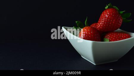 un primo piano di fragola su sfondo nero perfetto per il copyspace Foto Stock